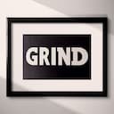 Matted frame view of A minimalist letterpress print, the word "GRIND"